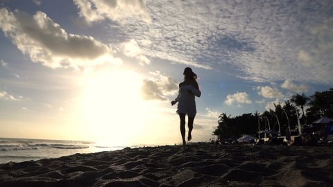 Sexy fit woman running on the beach during sunset, super slow motion