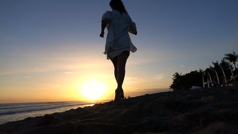 Sexy fit woman running on the beach during sunset, super slow motion