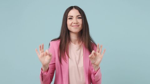 Young woman 20s years old wears pink jacket t-shirt dance clenching fists waving rising gesticulating hands fooling around have fun enjoy celebrate isolated on pastel blue wall color background studio