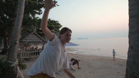 The girl goes on a slackline at sunset on a tropical beach.
