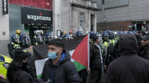 LONDON, UK – May 15, 2021: Free Palestine protesters hold Palestine flag and chant in front of riot police at free Palestine protest outside Embassy of Israel in London, England, UK