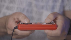 Nerd plays with red retro video game. Male game player. Hands close up