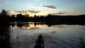 Slow motion video girl at sunset pours water on herself lake summer water trees 120 fps