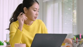 Young attractive business asian woman talking about sale report in video call conference on notebook computer online meeting in working from home, Working remotely and Social isolation concept.
