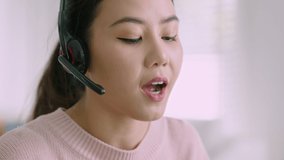 Asian woman wear wireless headset making conference video call on laptop. Professional call center agent, hr manager having distance webcam chat job interview on computer at home office.