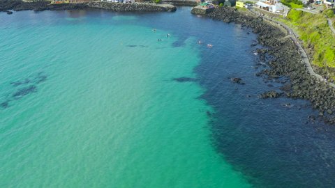 Tourists kayaking in the clear blue sea of Jeju Island.