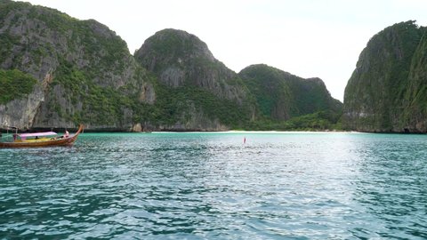 Taking boat in Maya bay with beautiful mountain, blue sea and long tail boat. Phi Phi islands, Krabi, Thailand.