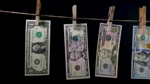 Dollars dry on a clothespin rope on a black background. The financial concept of the dollar. Money laundering concept.