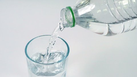 Close up slow motion pouring fresh drink water into drinking glass