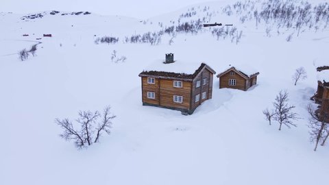 Traditional large classic log cabin in the mountains on a snowy cold winters day. 4K Aerial fly over.