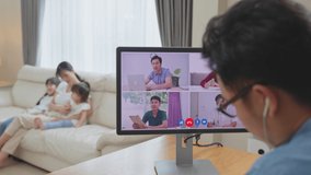 Asian Working business man father talk to colleagues team on virtual video call conference online. Male freelance worker using laptop computer, work at home due Covid-19 lockdown with family in house.