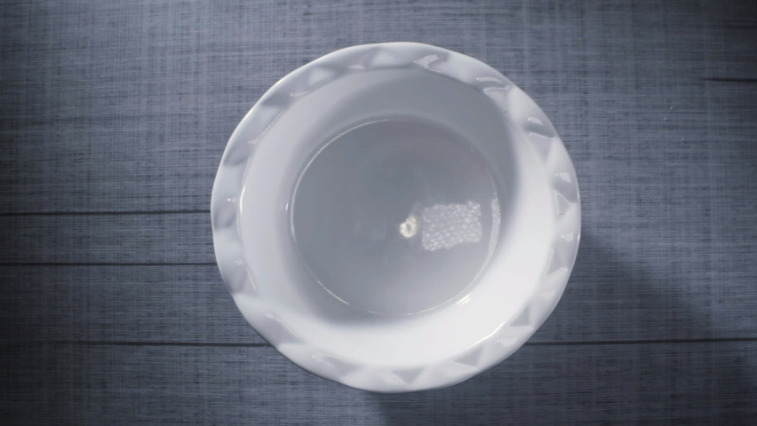 Colorful fruit cereal breakfast falls into bowl with milk being poured in slow motion 