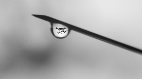 vaccination, drugs kill concept, dripping drops from the syringes needle close up. lethal dose. skull in a drop. death at the tip. soft grey gradient background. horizontal slow motion macro HD video.