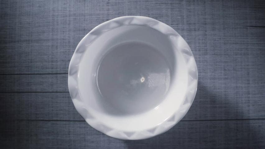 Colorful fruit cereal flake pebbles breakfast falls into bowl with milk being poured in slow motion 