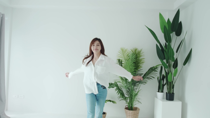 SLOW MOTION Tracking in Asian woman with a white shirt spins frottage feel good in a white room