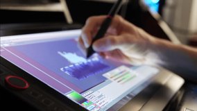 A digital artist creating a cartoon character with retro pixel art in a video game development studio on a touch screen drawing tablet with stylus pen SLIDE.