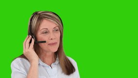 Senior woman with an headset talking against a green screen