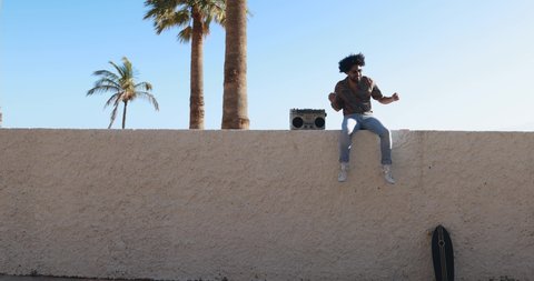 Young african man dancing outdoor with vintage boombox - Party and summer lifestyle concept