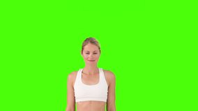 Blond female in sportswear doing exercise against a green screen