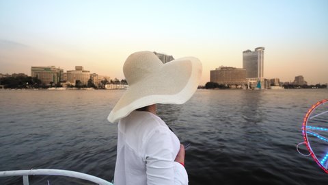 Tourist women with straw hat on cruise boat on Nile river, enjoying the skyline of Cairo, Egypt. Travling and vacation in Egypt