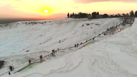 Visitors and tourist people walks touring calcium carbonate travertines.Travertine terrace formations.Sedimentary rock deposited by waters from the hot spring.Pamukkale cotton castle natural limestone