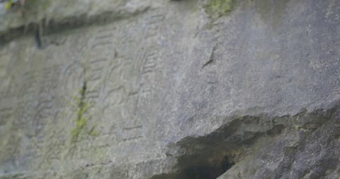 Beautiful ancient Chinese characters edged into the stone on the side of a mountain.