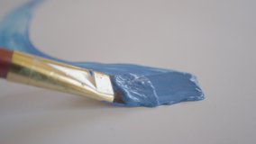 CLOSE UP, DOF: Detailed shot of a brush drawing a curved line with light blue paint as unrecognizable painter drags their fine brush across the blank canvas. Artist paints with blue acrylic paint - Powered by Shutterstock - Get 15% off with code: PIKWIZARD15