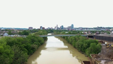 4K Aerial video shot of W 11th Street Bridge from Covington into Newport with the Cincinnati skyline in the background while the camera dollies in. Concrete bridge crossing muddy river in the midwest.