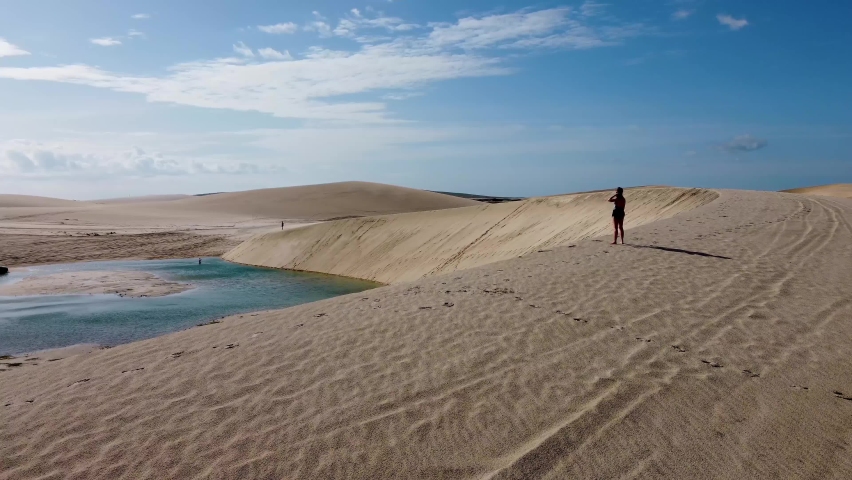 Beauty woman walking at peak dune. Travel scenery on exotic tropical destinations. Sand dunes on beach landscape. Tropical travel. Vacation travel. Jericoacoara, Ceara, Brazil. Brazilian caribbean.
