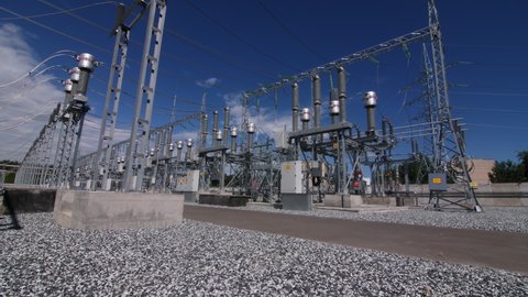 Motion along territory of large electrical distribution substation across road to powerful transformer with ceramic insulators
