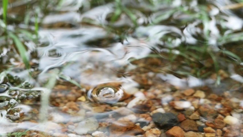 Water drops over the water on gravel bachground during the rain. Nature rainy season background.