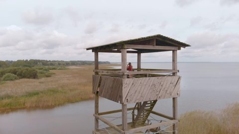 Woman birdwatching at watchtower Vortsjarv lake Estonia