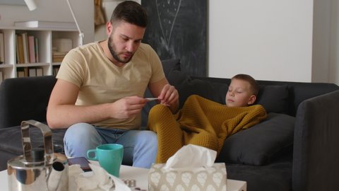 father gives tea to his son. son has flu