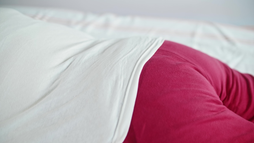 Old woman lies on bed and man puts special coil on her rump to cure. Alternative medecine.