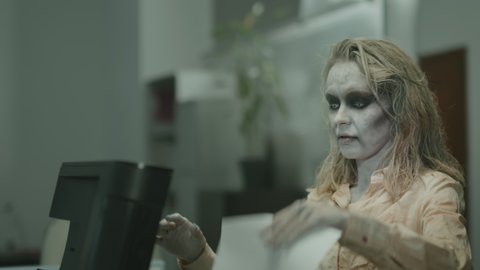 Handheld slowmo tracking of zombie businesspeople with SFX makeup and white contact lenses making photocopies and working in office