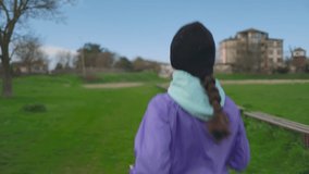 Jog in the park. A young woman in a hat is running. Back view, close-up. Follow shot. Sports Lifestyle Concept.