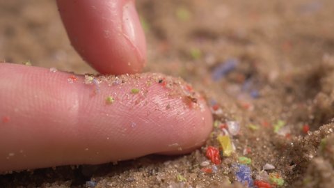 hands showing microplastics on the beach. small plastic pieces harmful to ocean and aquatic life. marine plastic debris.