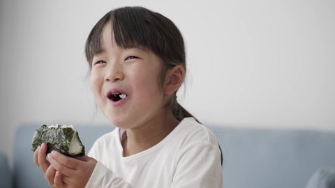 young asian girl eating onigiri
