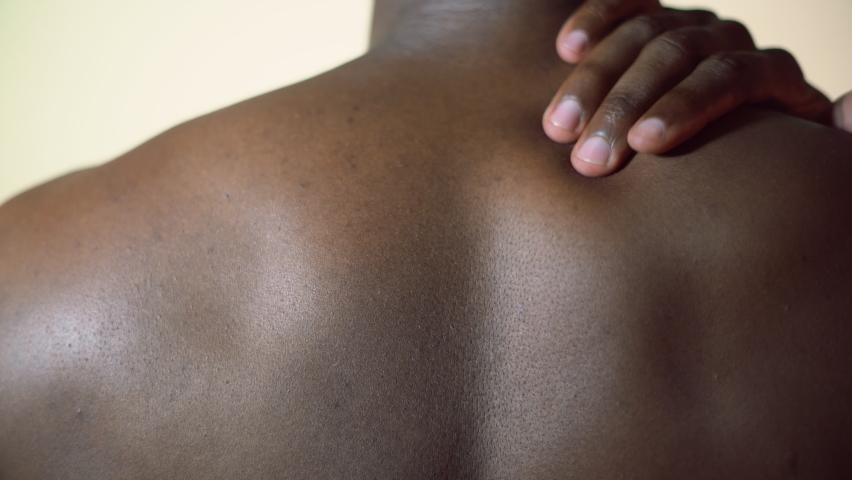 Closeup view of an African male rubbing his right shoulder. Black man experiencing shoulder Pain. 