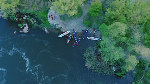 Aerial view of the winning rowers disembarking from boat races on the river. Rowers after the race gathering to award the winners of the competition. Racing boats are moored to the river bank.