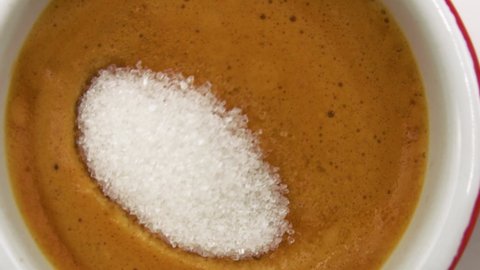 Close-up of a teaspoon of sugar that dips gently into a cup of italian coffee.breakfast.coffee break.macro
