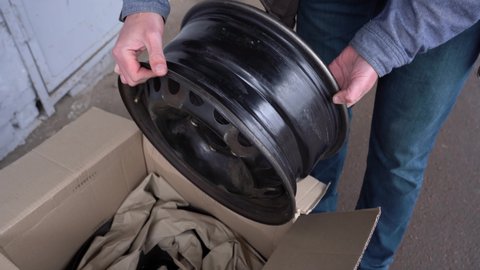 Closeup view 4k stock video footage of opened cardboard delivery box and old used steel wheel rims bought online through internet. Driver just received them in post office of delivery service