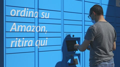 Lipomo, Como Italy - May 18, 2021: person who collects a shipment from Amazon Locker, automated delivery system.