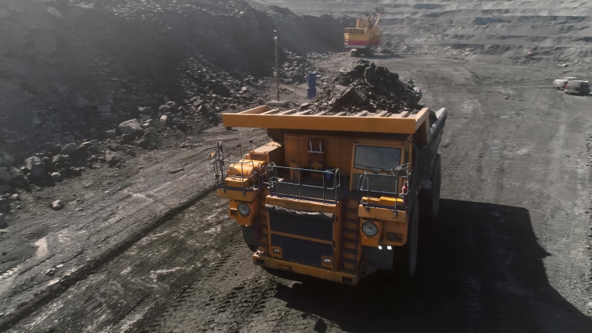 Large quarry dump truck. Loading rock in dumper. Loading coal into truck. Mining car machinery to transport coal. Open pit mine quarrying extractive industry stripping work. Big Yellow Mining Trucks | Shutterstock HD Video #1072639040