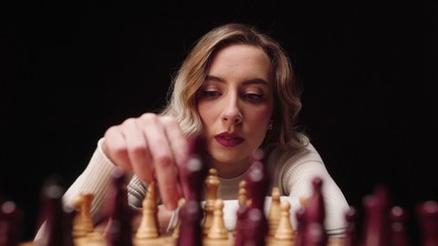 Beautiful Girl Playing Chess Board Game And Moving Pawn Piece With Black Background. - close up, POV