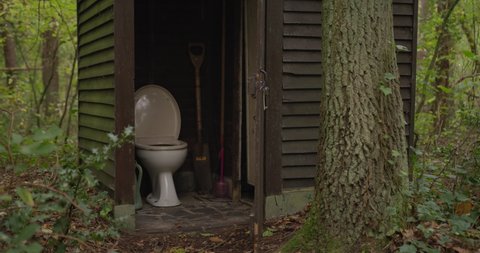 Outdoor toilet in the woods. Restroom in a wooden shed in a forest.Outdoor toilet in the middle of a forest. Outhouse between the trees. A dated lavatory in nature. WC in woodlands. Toilet in a shack.