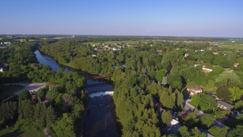 Incredible aerial view of a small town with a river in rural Ontario. Pull back drone shot, wide aerial view.