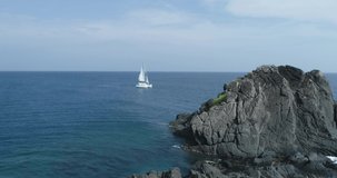 The yacht sails on the ocean, the yacht floats out of the rocks, video footage from a bird's eye view, the yacht is recorded from a drone. The yacht is sailing in Thailand.   in Phuket