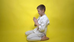 boy in a kimono performs a greeting before starting a workout on a yellow background close-up, Ritsu Rei respect in sports sports, karate, aikido, judo, wushu, taekwondo Sports lifestyle. Martial Arts