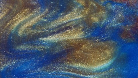 Fluid art. Liquid abstractions. Starry gold dust. Abstract bright red and light pastel streams with gold dust spread across the plane on a blue background. Marble texture.